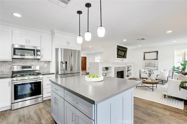 55 Fairfield, Lake Forest, CA 92610 - kitchen featuring stainless steel appliances, open floor plan, light wood-style flooring, tasteful backsplash, and a center island