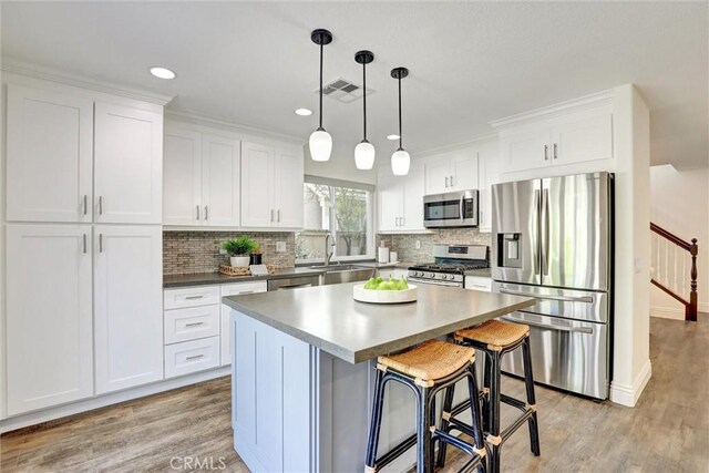 55 Fairfield, Lake Forest, CA 92610 - kitchen featuring stainless steel appliances, a kitchen island, tasteful backsplash, white cabinets, and recessed lighting