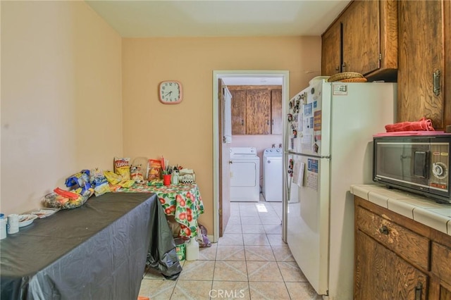 14012 S Wilkie Ave, Gardena, CA 90249 - kitchen with black microwave, washing machine and dryer, tile countertops, freestanding refrigerator, and brown cabinets