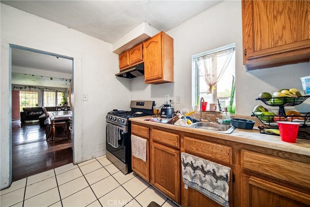 633 E 136th St, Los Angeles, CA 90059 - kitchen featuring gas range, light countertops, brown cabinetry, under cabinet range hood, and light tile patterned floors