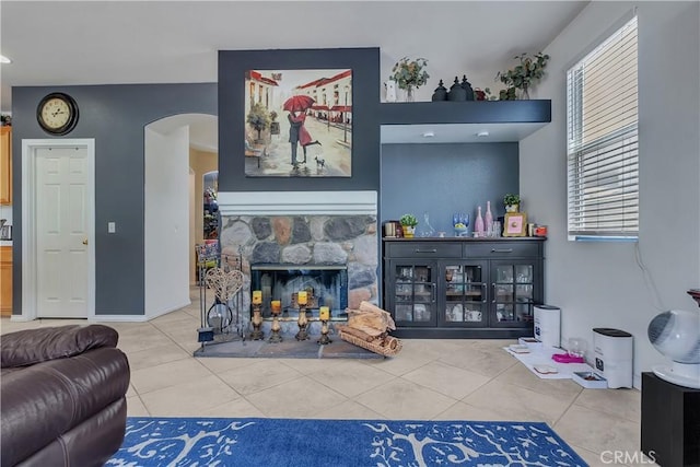 11244 Sega Ln, Fontana, CA 92337 - living room featuring arched walkways, tile patterned flooring, and a stone fireplace