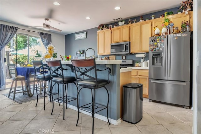 11244 Sega Ln, Fontana, CA 92337 - kitchen with stainless steel appliances, light brown cabinetry, a ceiling fan, light tile patterned flooring, and recessed lighting