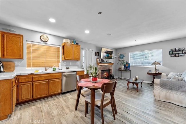 13519 Fremont St, Fontana, CA 92336 - kitchen featuring stainless steel dishwasher, open floor plan, light wood finished floors, tile countertops, and a brick fireplace