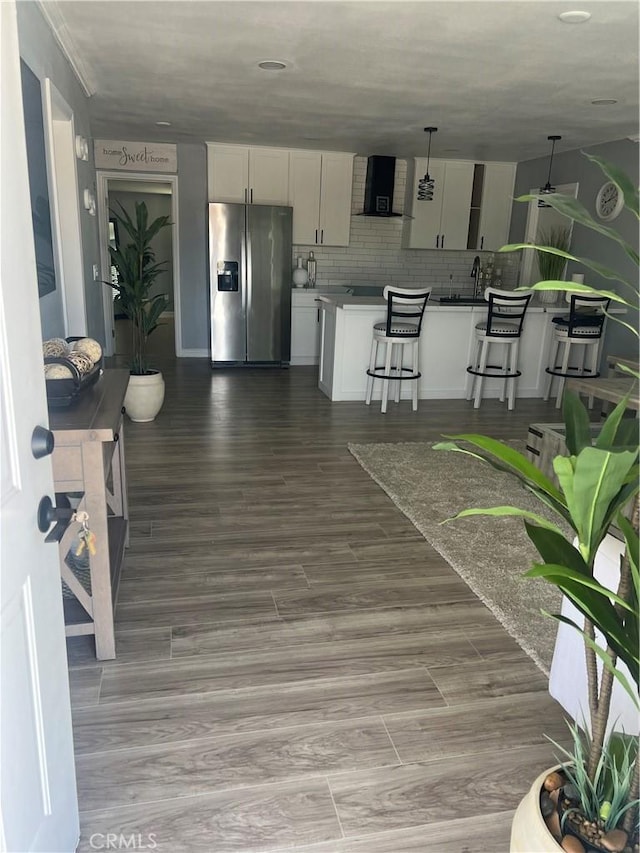 14726 Osage Rd, Apple Valley, CA 92307 - kitchen featuring stainless steel fridge, wall chimney range hood, a kitchen bar, white cabinetry, and decorative backsplash