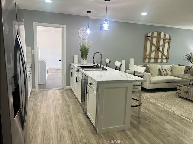 14726 Osage Rd, Apple Valley, CA 92307 - kitchen with stainless steel refrigerator with ice dispenser, a breakfast bar area, light wood finished floors, washer / dryer, and white cabinets