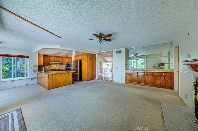1736 Island Dr, Fullerton, CA 92833 - kitchen featuring stainless steel appliances, brown cabinets, under cabinet range hood, open floor plan, and a peninsula