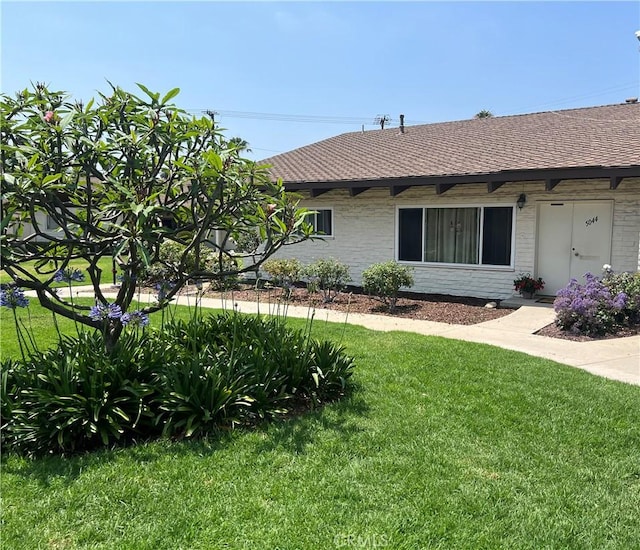 5044 Lakeview Ave Unit 23, Yorba Linda, CA 92886 - view of side of home featuring a lawn, roof with shingles, and brick siding