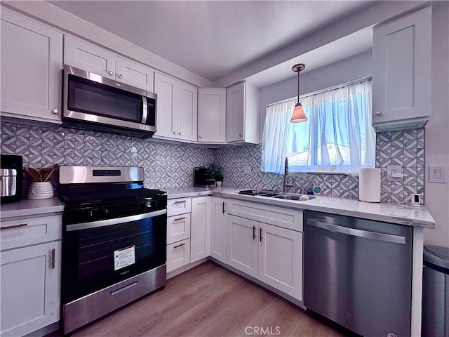 2969 Crestwood Pl, Riverside, CA 92503 - kitchen with stainless steel appliances, a sink, light countertops, light wood-style floors, and white cabinets