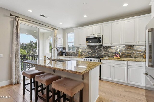 3224 Lisbon Ln, Oxnard, CA 93036 - kitchen featuring stainless steel microwave, a sink, tasteful backsplash, light stone countertops, and white cabinets