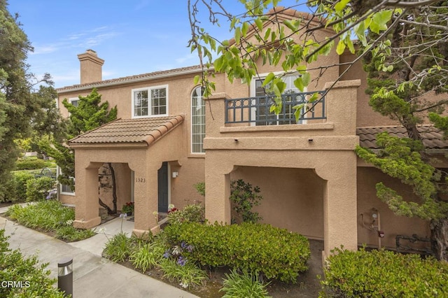 1323 Lost Point Ln, Oxnard, CA 93030 - view of front facade featuring a balcony, a chimney, stucco siding, and a tiled roof