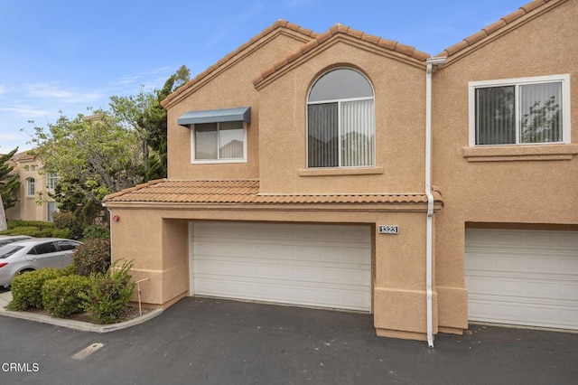 1323 Lost Point Ln, Oxnard, CA 93030 - townhome / multi-family property with an attached garage, a tiled roof, stucco siding, and driveway