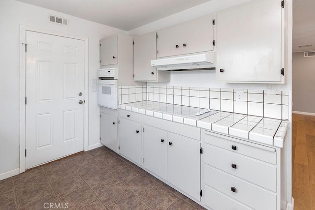 3760 Fielding Cir, Sacramento, CA 95826 - kitchen with under cabinet range hood, white appliances, tile counters, and tasteful backsplash