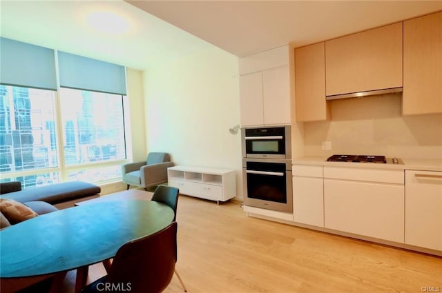 877 Francisco St Unit 1903, Los Angeles, CA 90017 - kitchen featuring gas cooktop, light wood-style floors, double oven, light countertops, and ventilation hood
