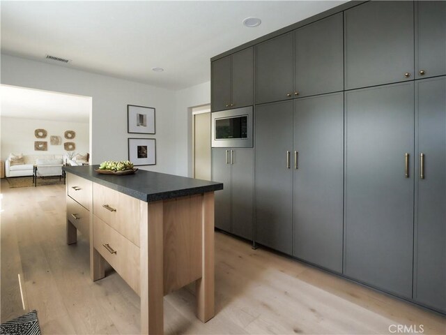 26633 Academy Dr, Palos Verdes Peninsula, CA 90274 - kitchen with stainless steel microwave, light wood finished floors, dark countertops, a center island, and modern cabinets
