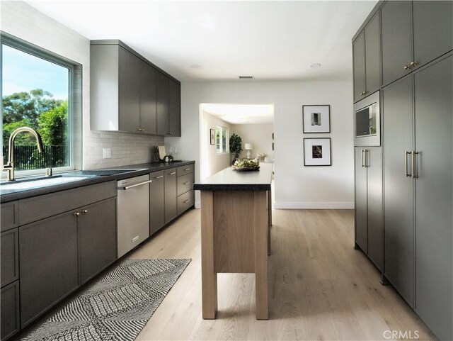 26633 Academy Dr, Palos Verdes Peninsula, CA 90274 - kitchen featuring appliances with stainless steel finishes, light wood finished floors, tasteful backsplash, a kitchen island, and dark countertops