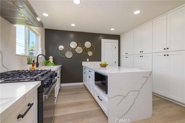 3567 Mount Everest Blvd, San Diego, CA 92111 - kitchen with black appliances, ventilation hood, light wood finished floors, white cabinetry, and recessed lighting