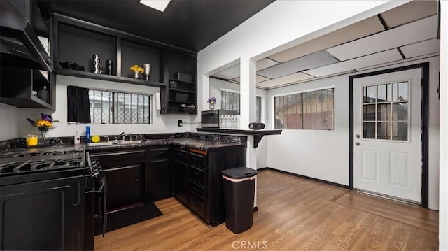 3902 Live Oak St, Cudahy, CA 90201 - kitchen featuring open shelves, gas stove, dark cabinetry, dark countertops, and healthy amount of natural light
