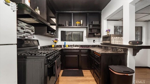 3902 Live Oak St, Cudahy, CA 90201 - kitchen with black gas range, freestanding refrigerator, ventilation hood, open shelves, and light wood finished floors