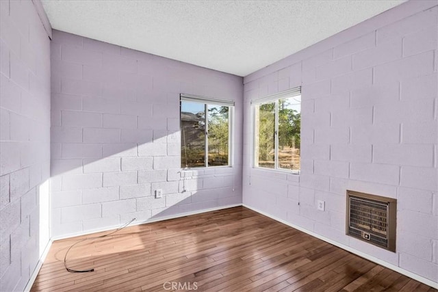 6646 Quail Spring Ave Unit 29, Palms, CA 92277 - unfurnished room featuring hardwood / wood-style flooring, a textured ceiling, a fireplace, and concrete block wall