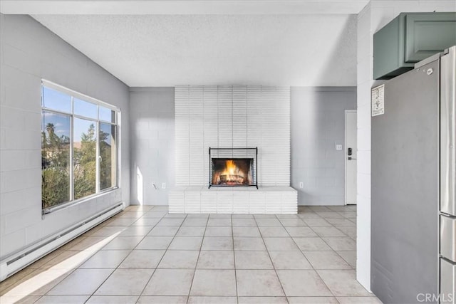 6646 Quail Spring Ave Unit 29, Palms, CA 92277 - unfurnished living room with a baseboard heating unit, a brick fireplace, light tile patterned flooring, and a textured ceiling