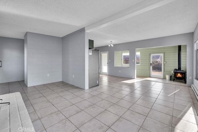 6646 Quail Spring Ave Unit 29, Palms, CA 92277 - unfurnished living room with a wood stove, a textured ceiling, light tile patterned flooring, and concrete block wall
