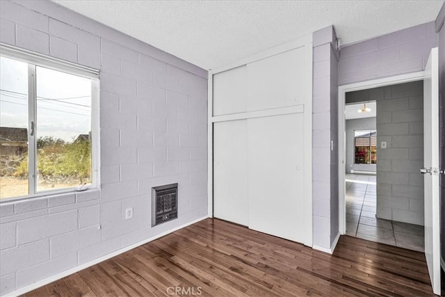 6646 Quail Spring Ave Unit 29, Palms, CA 92277 - unfurnished bedroom with concrete block wall, dark wood-type flooring, a closet, a fireplace, and heating unit