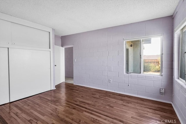 6646 Quail Spring Ave Unit 29, Palms, CA 92277 - unfurnished bedroom featuring wood finished floors, a textured ceiling, concrete block wall, and a closet