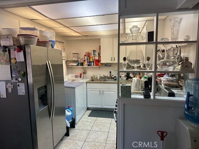 2440 Merrywood St, Pomona, CA 91767 - kitchen with stainless steel fridge, light tile patterned flooring, washer / dryer, white cabinets, and open shelves