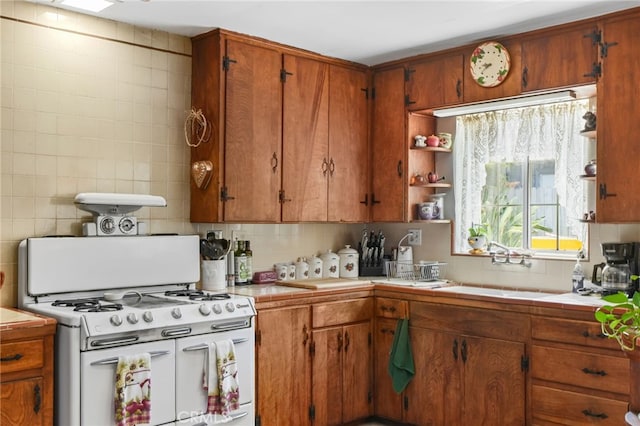 3095 Casitas Ave, Altadena, CA 91001 - kitchen featuring white range with gas stovetop, tile counters, backsplash, a sink, and brown cabinets