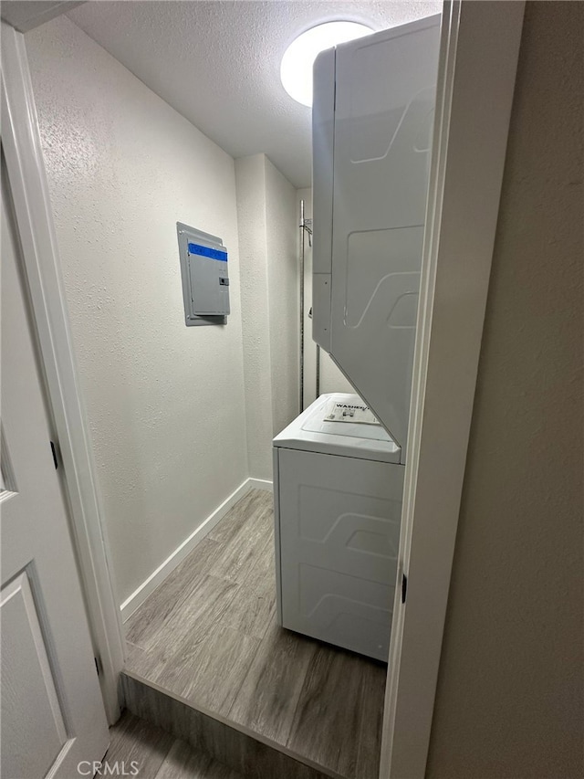 829 Foxworth Ave, La Puente, CA 91744 - laundry area featuring estacked washer and dryer, wood finished floors, electric panel, and a textured ceiling