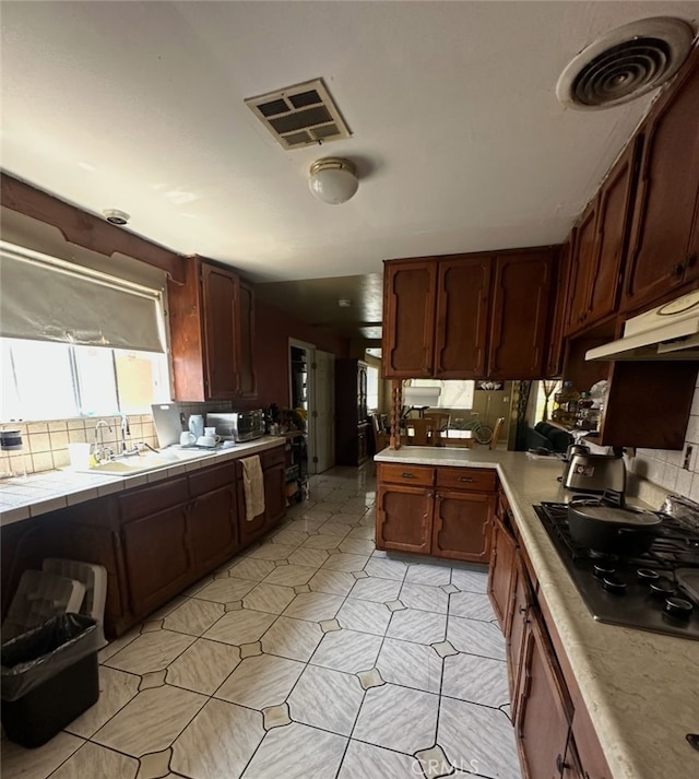 829 Foxworth Ave, La Puente, CA 91744 - kitchen featuring gas cooktop, backsplash, tile counters, and under cabinet range hood