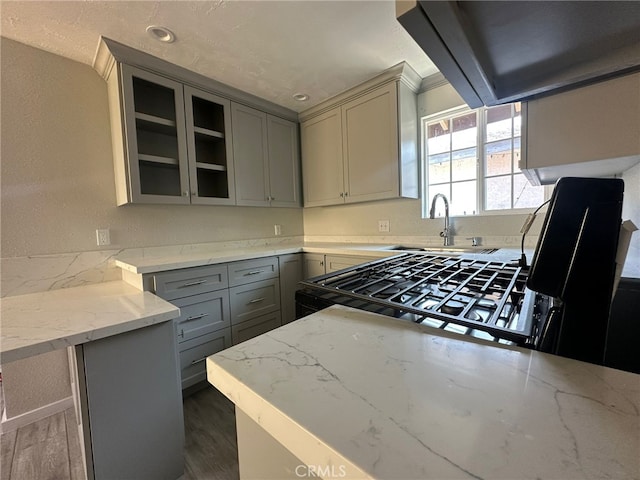 829 Foxworth Ave, La Puente, CA 91744 - kitchen featuring gray cabinetry, light stone countertops, range hood, dark wood-style floors, and crown molding