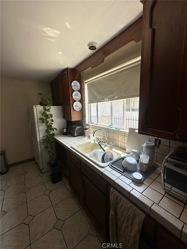 829 Foxworth Ave, La Puente, CA 91744 - kitchen with tile counters, freestanding refrigerator, backsplash, and dark brown cabinetry