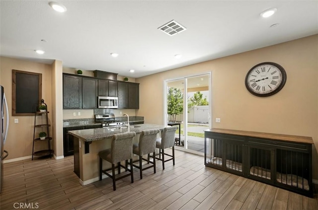 17995 Lacebark Ct, San Bernardino, CA 92407 - kitchen featuring appliances with stainless steel finishes, a breakfast bar, a center island with sink, wood finished floors, and recessed lighting
