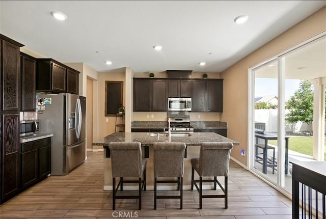 17995 Lacebark Ct, San Bernardino, CA 92407 - kitchen featuring stainless steel appliances, dark brown cabinetry, dark stone counters, light wood-type flooring, and recessed lighting