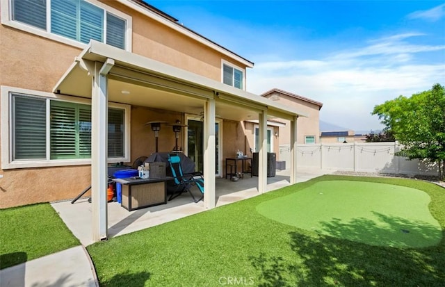 17995 Lacebark Ct, San Bernardino, CA 92407 - rear view of property featuring stucco siding, a putting green, a patio, and a fenced backyard
