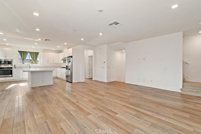 2750 182nd St Unit 112, Torrance, CA 90504 - unfurnished living room featuring light wood-style floors, a sink, recessed lighting, baseboards, and stairs