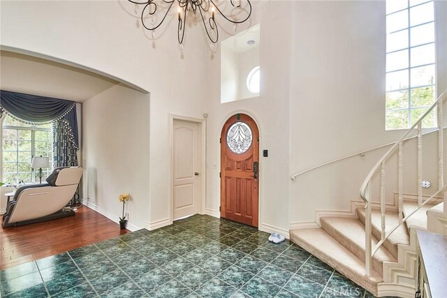 1089 Village Dr, Chino Hills, CA 91709 - foyer with a chandelier, stairway, arched walkways, a towering ceiling, and baseboards