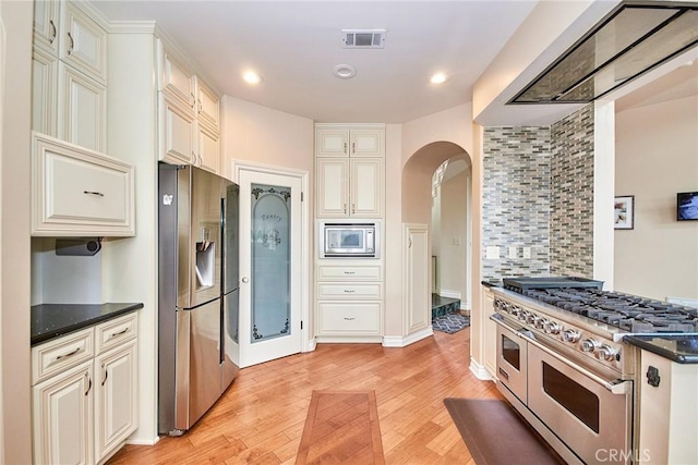1089 Village Dr, Chino Hills, CA 91709 - kitchen featuring appliances with stainless steel finishes, arched walkways, light wood finished floors, cream cabinets, and recessed lighting