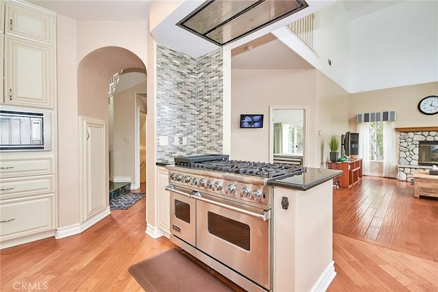 1089 Village Dr, Chino Hills, CA 91709 - kitchen with double oven range, a towering ceiling, light wood-style flooring, arched walkways, and cream cabinetry
