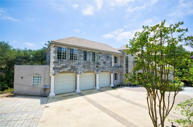 1089 Village Dr, Chino Hills, CA 91709 - view of front of home featuring concrete driveway, stone siding, a garage, and stucco siding