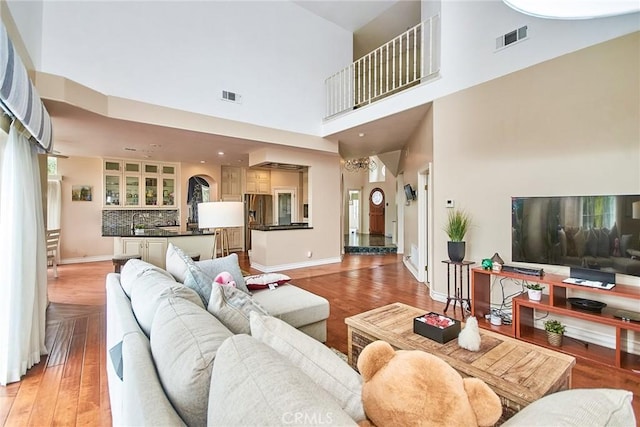 1089 Village Dr, Chino Hills, CA 91709 - living room featuring light wood-style flooring, a towering ceiling, baseboards, and arched walkways