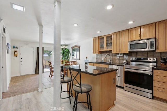 10161 Larwin Ave Unit 3, Chatsworth, CA 91311 - kitchen with appliances with stainless steel finishes, a center island, backsplash, a kitchen bar, and recessed lighting