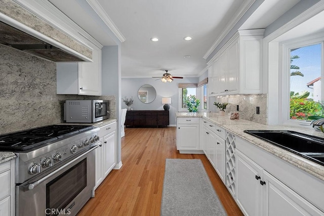 1609 Via Montemar, Palos Verdes Estates, CA 90274 - kitchen with stainless steel appliances, wall chimney range hood, ornamental molding, white cabinetry, and backsplash
