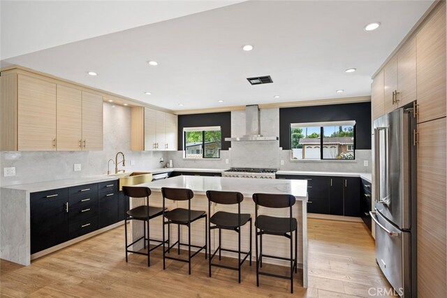 4801 Heaven Ave, Woodland Hills, CA 91364 - kitchen with freestanding refrigerator, wall chimney range hood, a sink, a kitchen bar, and backsplash