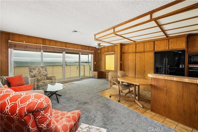 1207 Seal Way, Seal Beach, CA 90740 - living area with wooden walls, a textured ceiling, light colored carpet, and light tile patterned floors