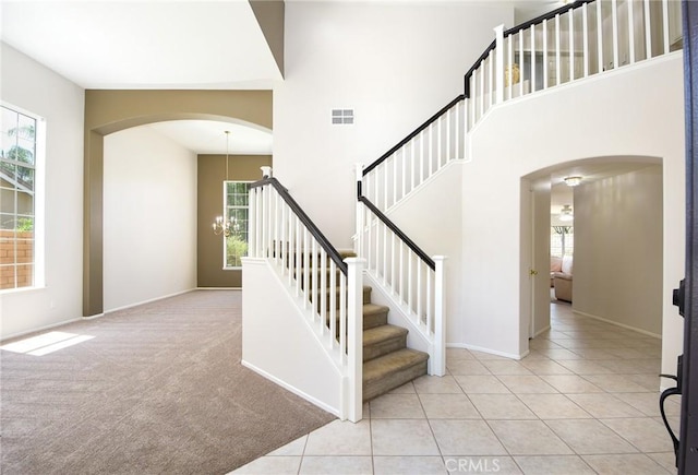 178 Grapevine Dr, Corona, CA 92882 - staircase featuring arched walkways, a chandelier, a towering ceiling, tile patterned floors, and baseboards