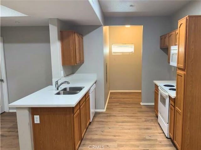 41410 Juniper St Unit 1513, Murrieta, CA 92562 - kitchen featuring white appliances, light wood finished floors, light countertops, brown cabinetry, and a peninsula