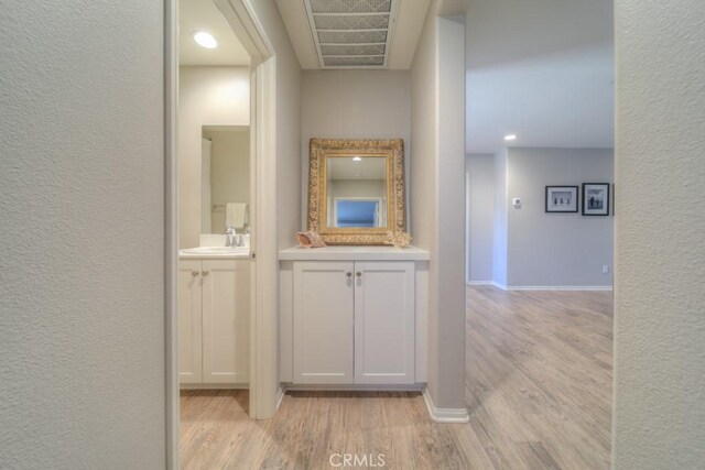 32593 Cumulus Ln, Winchester, CA 92596 - corridor with light wood-style floors, a sink, a textured wall, baseboards, and recessed lighting