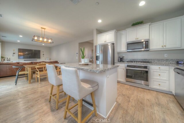 32593 Cumulus Ln, Winchester, CA 92596 - kitchen with stainless steel appliances, open floor plan, a center island, white cabinetry, and light wood-style floors
